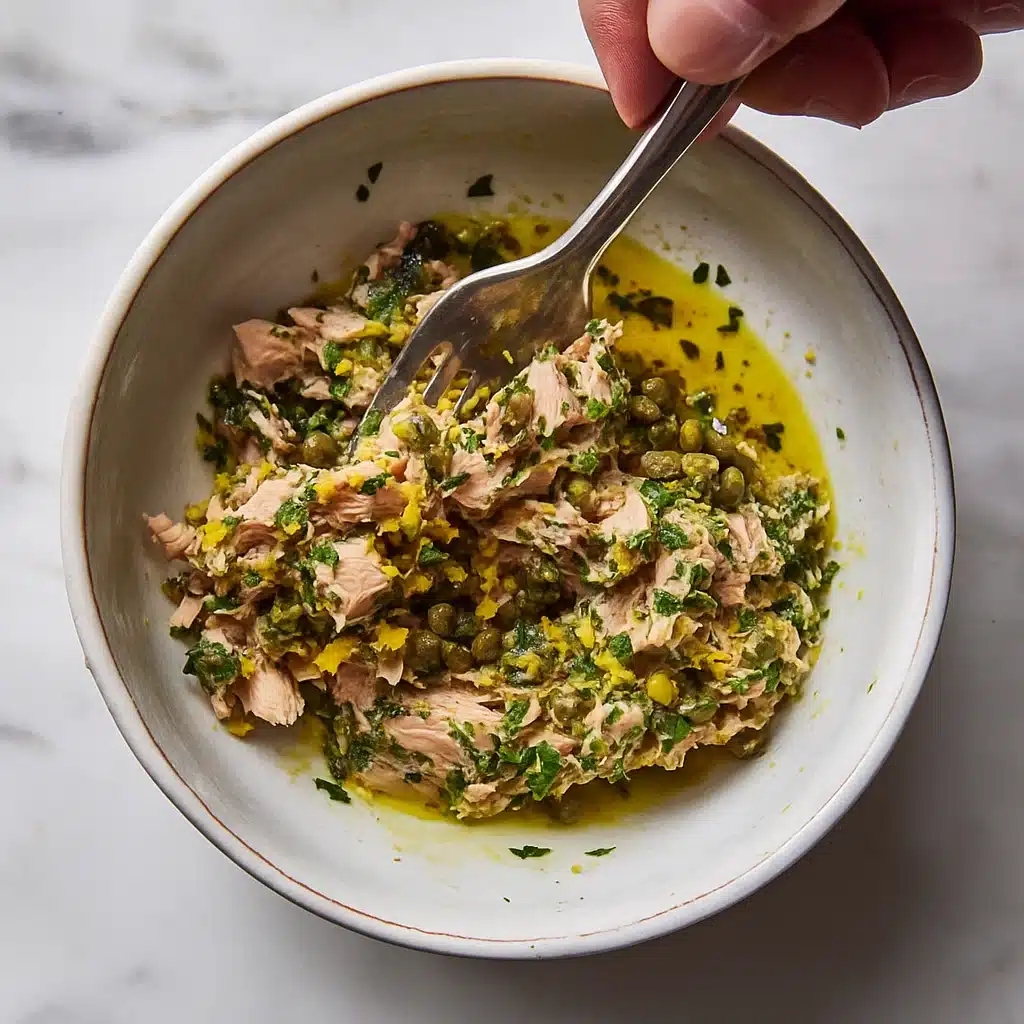 Mixing tuna, lemon, capers, olive oil, parsley in ceramic bowl