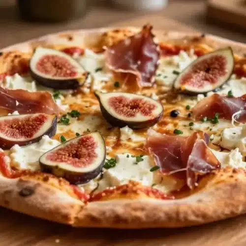 Delicious Fig Jam Pizza topped with goat cheese and prosciutto slices.